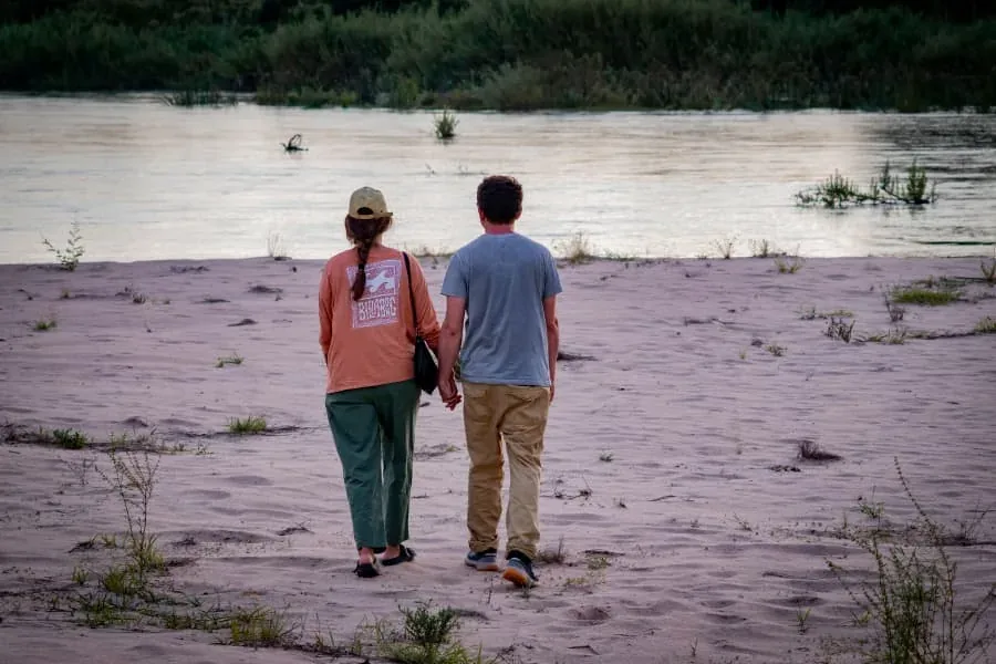 Couple walking toward a river at sunset on a Tanzania romantic safari
